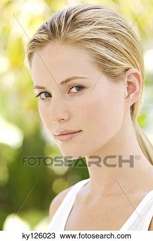 Portrait of a young woman looking at the camera, outdoors View Large Photo Image Stock Image - Portrait of a young woman looking at the camera, outdoors. Fotosearch