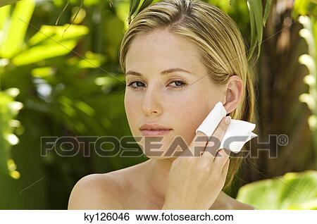 Portrait of a young woman using a cleansing cotton on her face, outdoors View Large Photo Image Stock Photograph - Portrait of a young woman using a cleansing cotton on her face, outdoors. Fotosearch