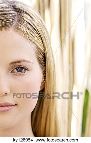 Picture - Portrait of half of a young woman's face, looking at the camera, close-up, outdoors. Fotosearch