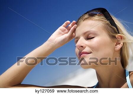 Portrait of a young woman with eyes closed, lifting up her sunglasses View Large Photo Image Stock Photo - Portrait of a young woman with eyes closed, lifting up her sunglasses. Fotosearch