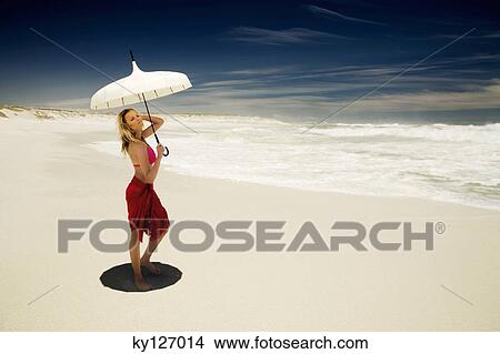 Picture - Young woman in bikini and pareo with parasol on the beach. Fotosearch