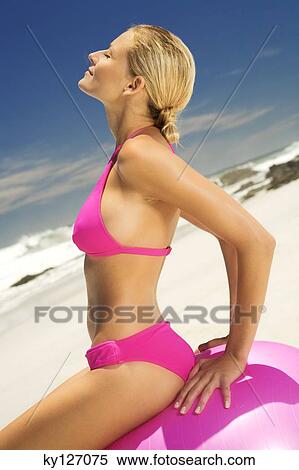 Young woman in pink bikini on the beach, sitting on a large ball View Large Photo Image Stock Photography - Young woman in pink bikini on the beach, sitting on a large ball. Fotosearch