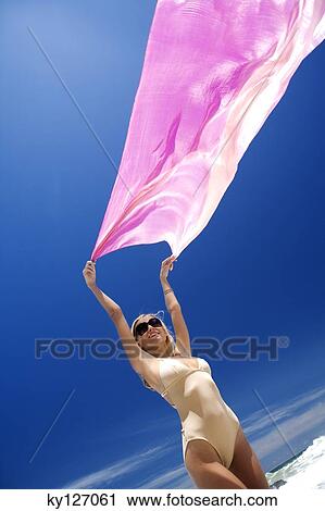 Young woman in swimming costume holding pink pareo in wind View Large Photo Image Stock Image - Young woman in swimming costume holding pink pareo in wind. Fotosearch