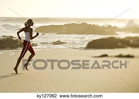 Young woman running on the beach View Large Photo Image Stock Image - Young woman running on the beach. Fotosearch