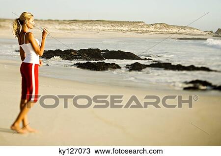 Young woman standing on beach, drinking water from a bottle View Large Photo Image Stock Image - Young woman standing on beach, drinking water from a bottle. Fotosearch