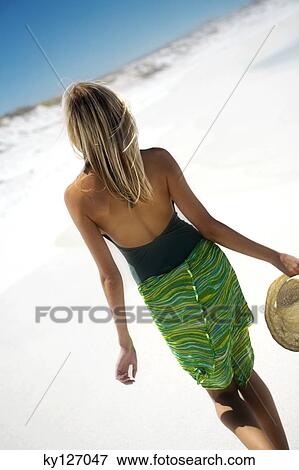 Young woman walking on the beach, rear view View Large Photo Image Stock Photo - Young woman walking on the beach, rear view. Fotosearch