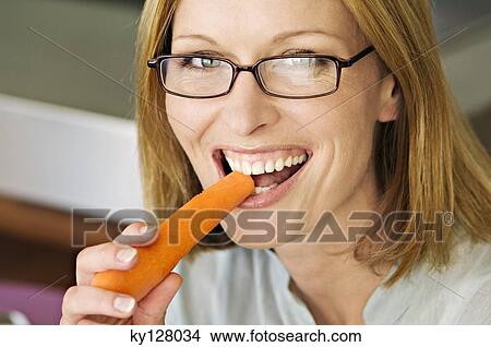 Picture - Portrait of a woman biting carrot. Fotosearch