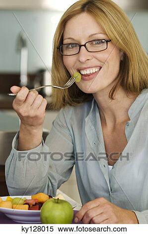 Stock Photography - Smiling woman eating fruit salad. Fotosearch