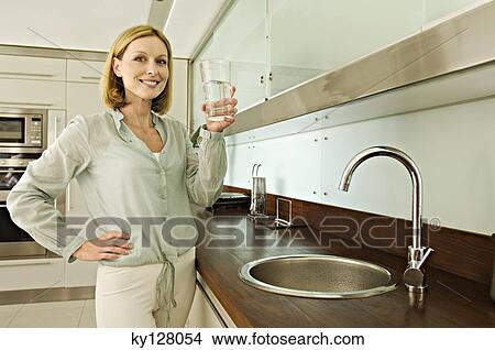 Smiling woman holding glass of water View Large Photo Image Picture - Smiling woman holding glass of water. Fotosearch