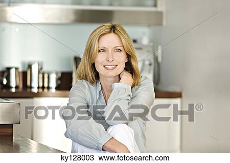 Smiling woman sitting in kitchen View Large Photo Image Stock Image - Smiling woman sitting in kitchen. Fotosearch