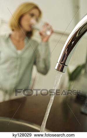 Woman drinking water, tap in foreground View Large Photo Image Stock Photo - Woman drinking water, tap in foreground. Fotosearch