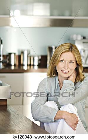Woman smiling for the camera in kitchen View Large Photo Image Stock Photo - Woman smiling for the camera in kitchen. Fotosearch