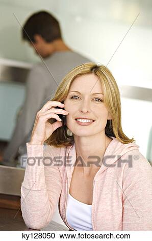 Woman using mobile phone, man in background View Large Photo Image Stock Image - Woman using mobile phone, man in background. Fotosearch
