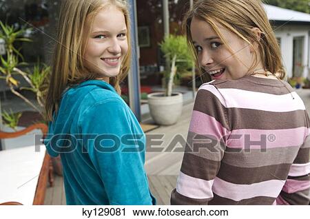 2 smiling teenage girls looking over shoulders View Large Photo Image Stock Image - 2 smiling teenage girls looking over shoulders. Fotosearch