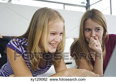 2 smiling teenage girls lying on bed, using laptop View Large Photo Image Stock Image - 2 smiling teenage girls lying on bed, using laptop. Fotosearch
