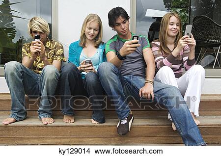 2 teenage boys and 2 teenage girls using their mobile phones View Large Photo Image Picture - 2 teenage boys and 2 teenage girls using their mobile phones. Fotosearch