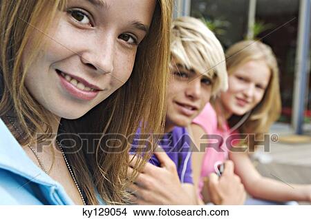 Picture - 2 teenage girls and teenage boy smiling for camera. Fotosearch