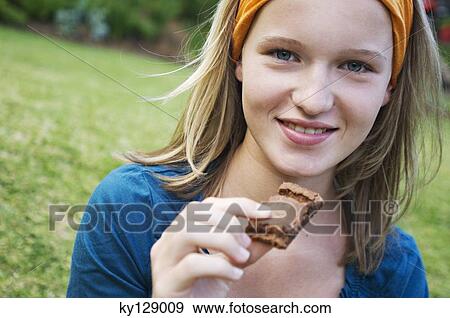 Portrait of a teenage girl holding piece of cake, outdoors View Large Photo Image Stock Photo - Portrait of a teenage girl holding piece of cake, outdoors. Fotosearch