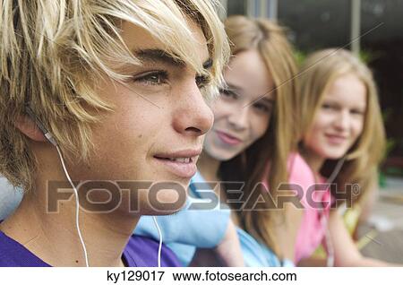 Portrait of teenage boy with earphones, 2 teenage girls in background View Large Photo Image Stock Photo - Portrait of teenage boy with earphones, 2 teenage girls in background. Fotosearch