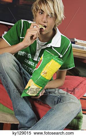 Teenage boy eating crisps View Large Photo Image Stock Photography - Teenage boy eating crisps. Fotosearch