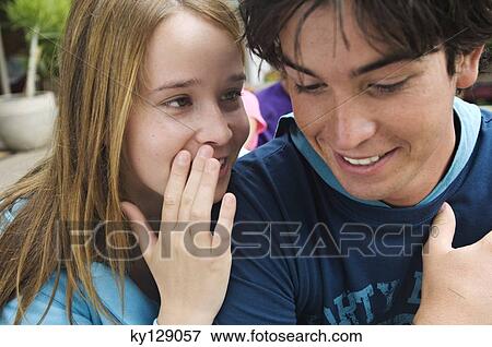 Stock Photo - Teenage girl whispering secrets to teenage boy. Fotosearch