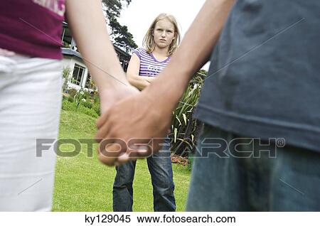 Teenagers holding hands, teen girl with arms crossed in background, outdoors View Large Photo Image Stock Photography - Teenagers holding hands, teen girl with arms crossed in background, outdoors. Fotosearch