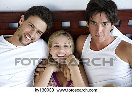 2 men and a woman lying in bed, smiling for the camera View Large Photo Image Stock Image - 2 men and a woman lying in bed, smiling for the camera. Fotosearch