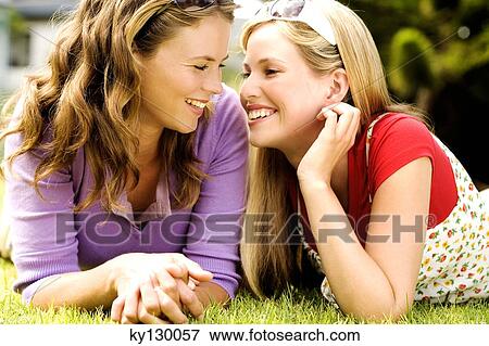 2 young smiling women lying on grass, looking at each other View Large Photo Image Stock Photo - 2 young smiling women lying on grass, looking at each other. Fotosearch