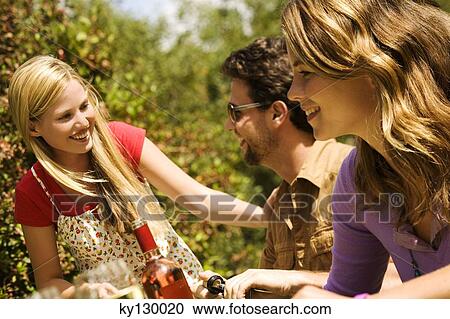 2 young women and a man sitting at garden table View Large Photo Image Stock Image - 2 young women and a man sitting at garden table. Fotosearch