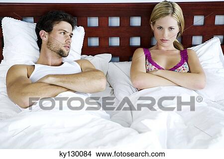 Young couple in bed, arms crossed View Large Photo Image Picture - Young couple in bed, arms crossed. Fotosearch