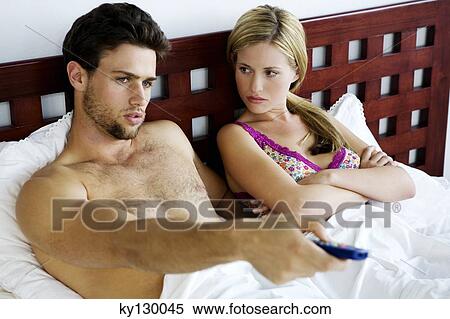 Young couple in bed, watching TV View Large Photo Image Stock Photography - Young couple in bed, watching TV. Fotosearch
