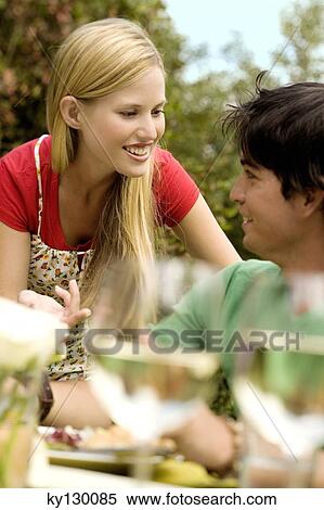Stock Photography - Young couple talking at garden table, outdoors. Fotosearch