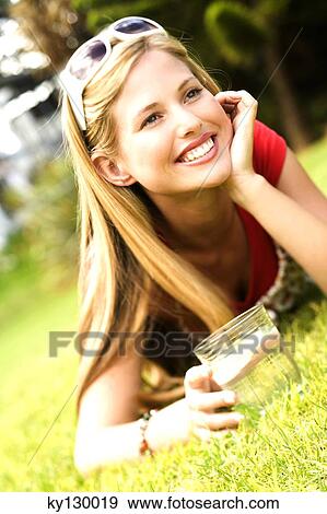Young smiling woman lying on grass, glass of water View Large Photo Image Stock Photo - Young smiling woman lying on grass, glass of water. Fotosearch