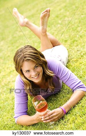 Young smiling woman lying on grass, glass of wine View Large Photo Image Stock Photo - Young smiling woman lying on grass, glass of wine. Fotosearch