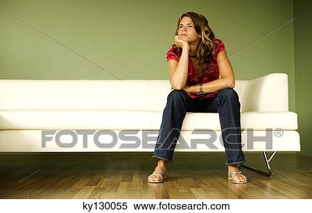 Young thinking woman sitting on a sofa View Large Photo Image Stock Photography - Young thinking woman sitting on a sofa. Fotosearch