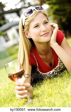 Young woman lying on grass, glass of wine View Large Photo Image Stock Image - Young woman lying on grass, glass of wine. Fotosearch