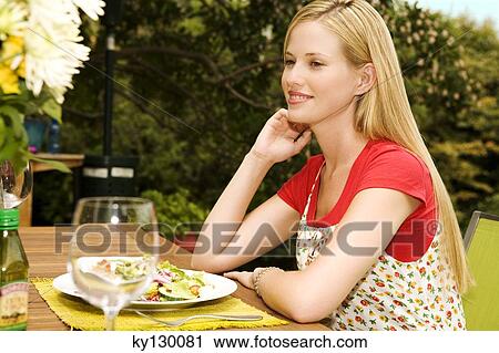 Young woman sitting at garden table View Large Photo Image Stock Image - Young woman sitting at garden table. Fotosearch