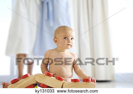 Baby playing, mother in background, indoors View Large Photo Image Stock Image - Baby playing, mother in background, indoors. Fotosearch
