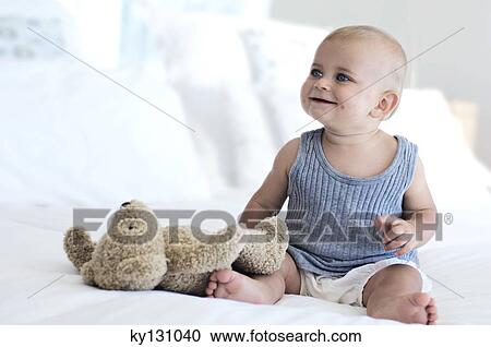 Baby sitting with teddy bear, indoors View Large Photo Image Stock Image - Baby sitting with teddy bear, indoors. Fotosearch