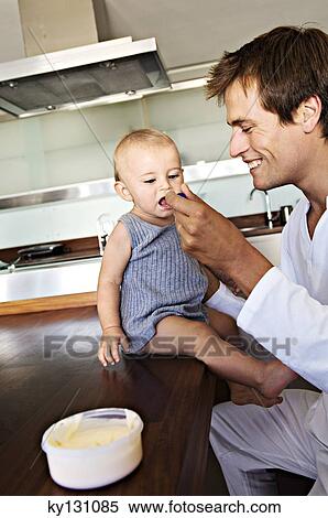 Father and son in kitchen, man feeding his baby, indoors View Large Photo Image Stock Photography - Father and son in kitchen, man feeding his baby, indoors. Fotosearch