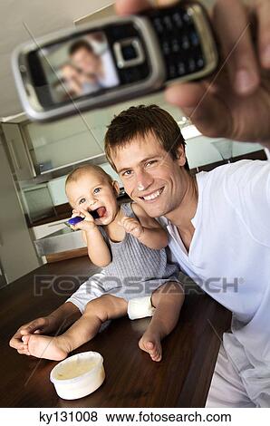 Father and son in kitchen, man taking a photograph of themselves, indoors View Large Photo Image Stock Photo - Father and son in kitchen, man taking a photograph of themselves, indoors. Fotosearch