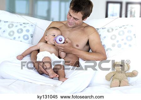 Stock Photography - Father feeding his baby, indoors. Fotosearch