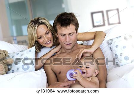 Father feeding his baby, mother looking at them, indoors View Large Photo Image Picture - Father feeding his baby, mother looking at them, indoors. Fotosearch