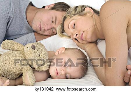 Stock Image - Father, mother and baby sleeping, indoors. Fotosearch