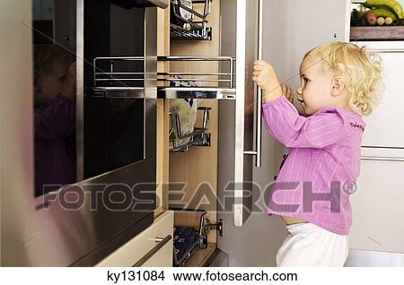 Little girl opening cabinets in kitchen, indoors View Large Photo Image Picture - Little girl opening cabinets in kitchen, indoors. Fotosearch