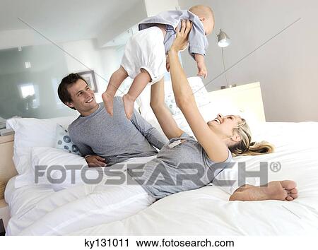 Parents and baby in bedroom, woman lifting her baby, indoors View Large Photo Image Stock Image - Parents and baby in bedroom, woman lifting her baby, indoors. Fotosearch