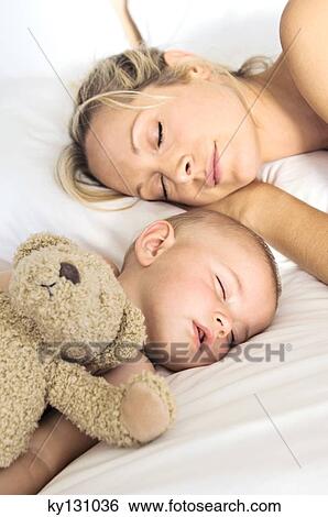 Stock Photograph - Portrait mother and her baby sleeping, indoors. Fotosearch