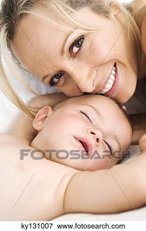 Portrait mother smiling and her baby sleeping, indoors View Large Photo Image Stock Photo - Portrait mother smiling and her baby sleeping, indoors. Fotosearch