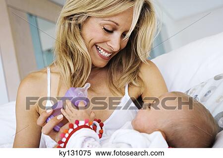 Portrait of a mother feeding her baby, indoors View Large Photo Image Stock Photography - Portrait of a mother feeding her baby, indoors. Fotosearch