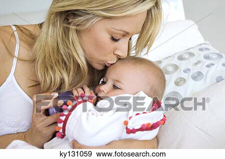 Portrait of a mother kissing her baby, indoors View Large Photo Image Stock Photo - Portrait of a mother kissing her baby, indoors. Fotosearch